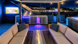 An outdoor living area with a grill, seating, and a TV screen. - Ultra Lux Home - Pool - Hot Tub - Fire pit! 14 Beds (Nashville)