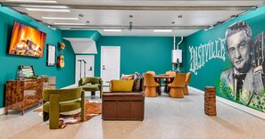 A room with teal walls, a fireplace, a dining area with chairs, and a large portrait mural. - Pool - Hot Tub - Golf-Fire pit 14 Beds (Nashville)