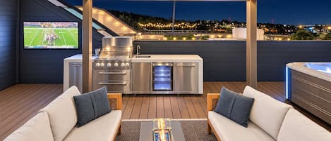 Un patio exterior con una parrilla, zona de estar y un jacuzzi.