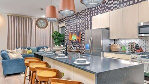 A modern kitchen with a central island, bar stools, a sofa, and a dining area. - Ultra Lux Home - Pool - Hot Tub - Fire pit! 14 Beds (Nashville)