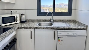 Une cuisine moderne équipée d’un four à micro-ondes, d’une bouilloire, d’un évier, d’une cuisinière et d’un lave-vaisselle.