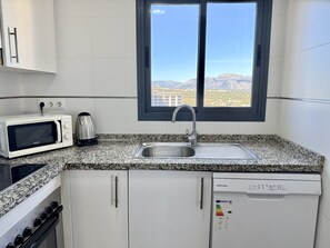 Eine moderne Küche mit Mikrowelle, Wasserkocher, Spüle, Herd und Geschirrspüler.
