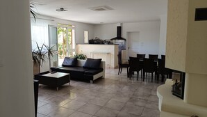 Een moderne woonkamer met een bank, salontafel en een eethoek met stoelen.