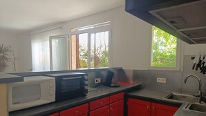 Een moderne keuken met rode kastjes, een magnetron, een broodrooster en een spoelbak.
