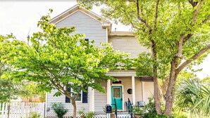 Una casa a un piano con portico, cassetta delle lettere e un piccolo giardino.