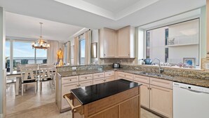 A spacious kitchen with a central island, granite countertops, and wooden cabinets. - Indigo West 304 by Liquid Life (Pensacola)