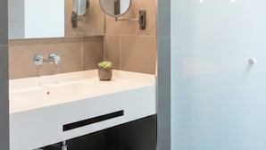 A modern bathroom with a large mirror, two wall-mounted lights, a sink, and a towel rack. - Hotel Ogar Tomelloso (Tomelloso)