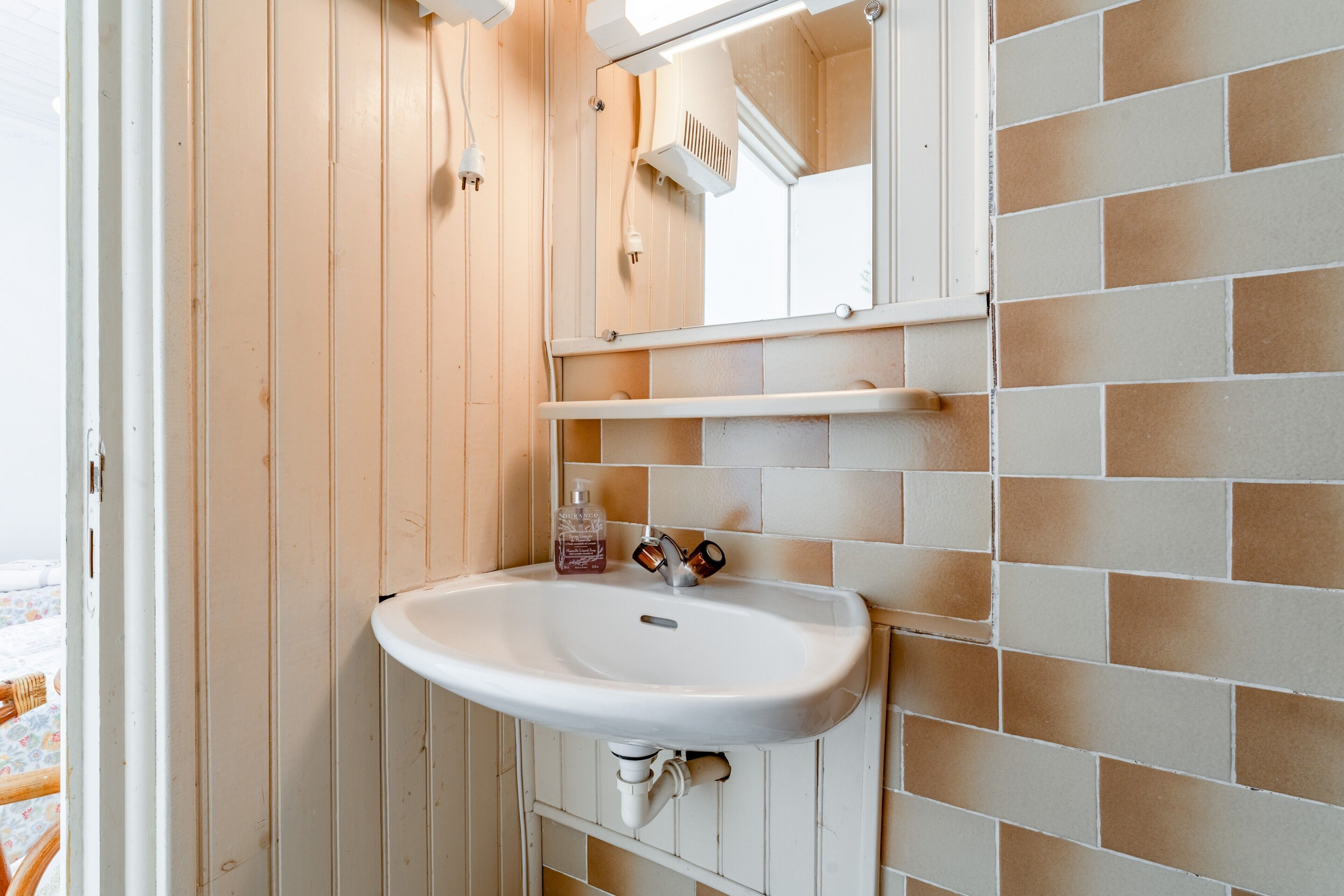 A bathroom with a white sink, mirror, and tiled walls.