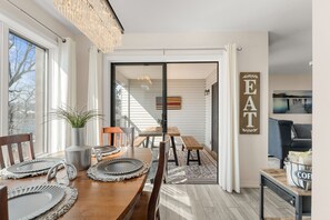 A dining area with a wooden table, chairs, and a view through a glass door to an outdoor space. - Lakefront Condo in Kimberling City_Free Attraction Tickets_Gorgeous View_Near Silver Dollar City (Kimberling City)