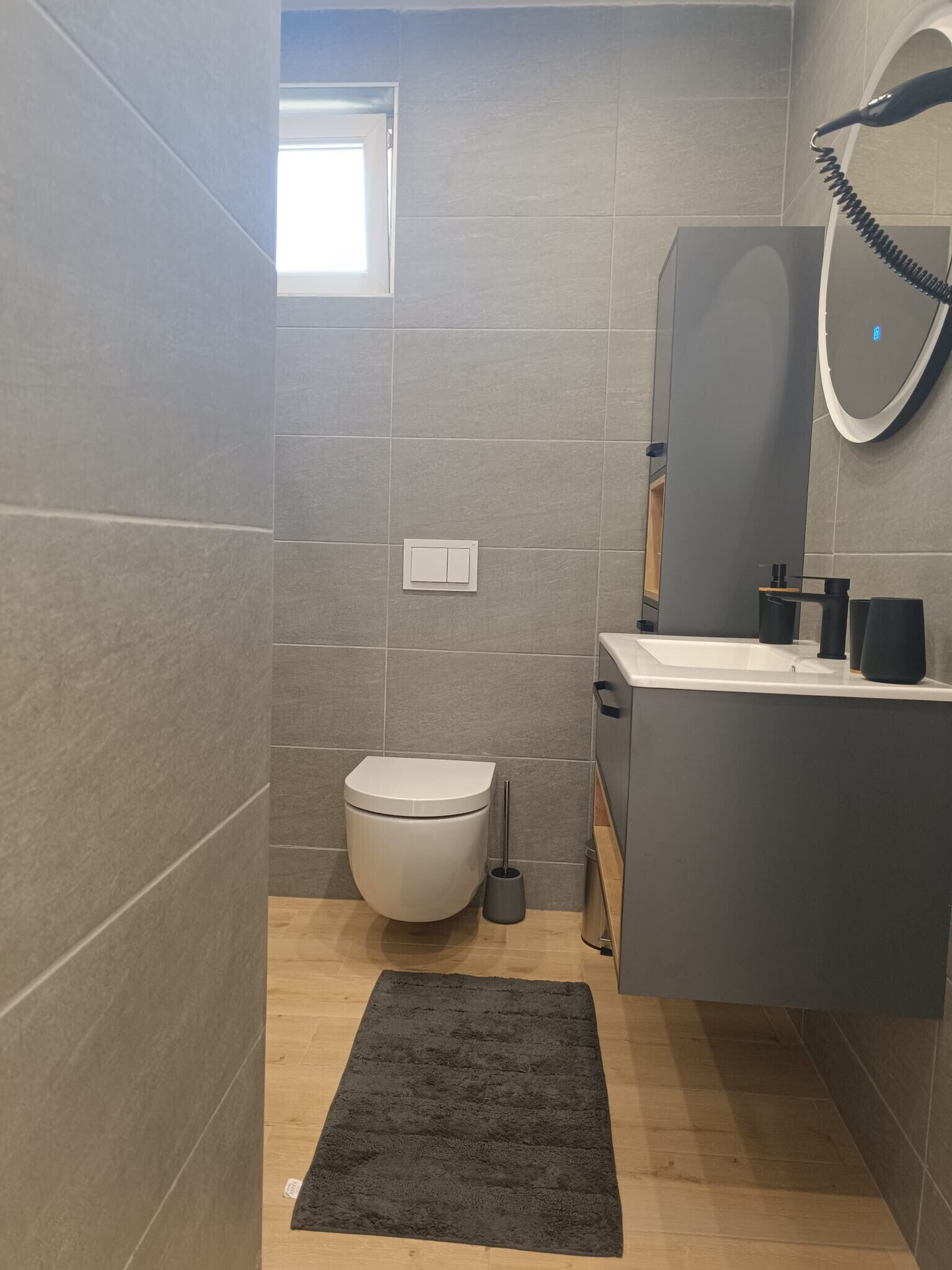 A modern bathroom with a toilet, sink, and mirror.