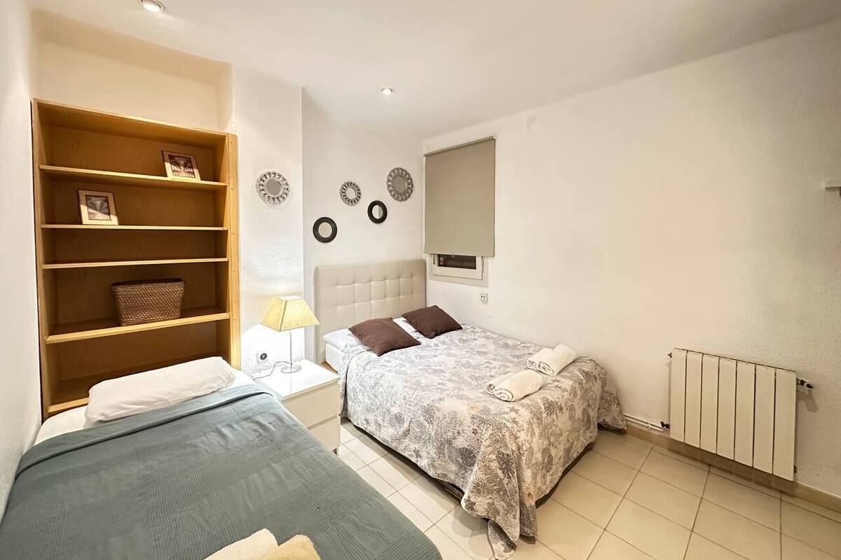 Un dormitorio con cama, mesita de noche, lámpara, armario y radiador.