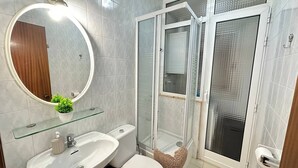 A bathroom with a white sink, toilet, and glass shower enclosure. - Rooms Consell de cent (Barcelona)