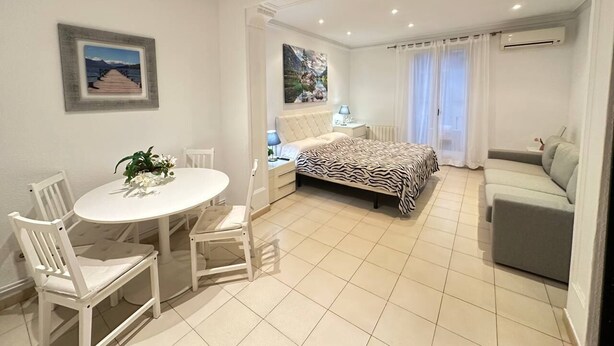 A modern bedroom with a bed, a sofa, a dining table with chairs, and a painting on the wall. - Rooms Consell de cent (Barcelona)