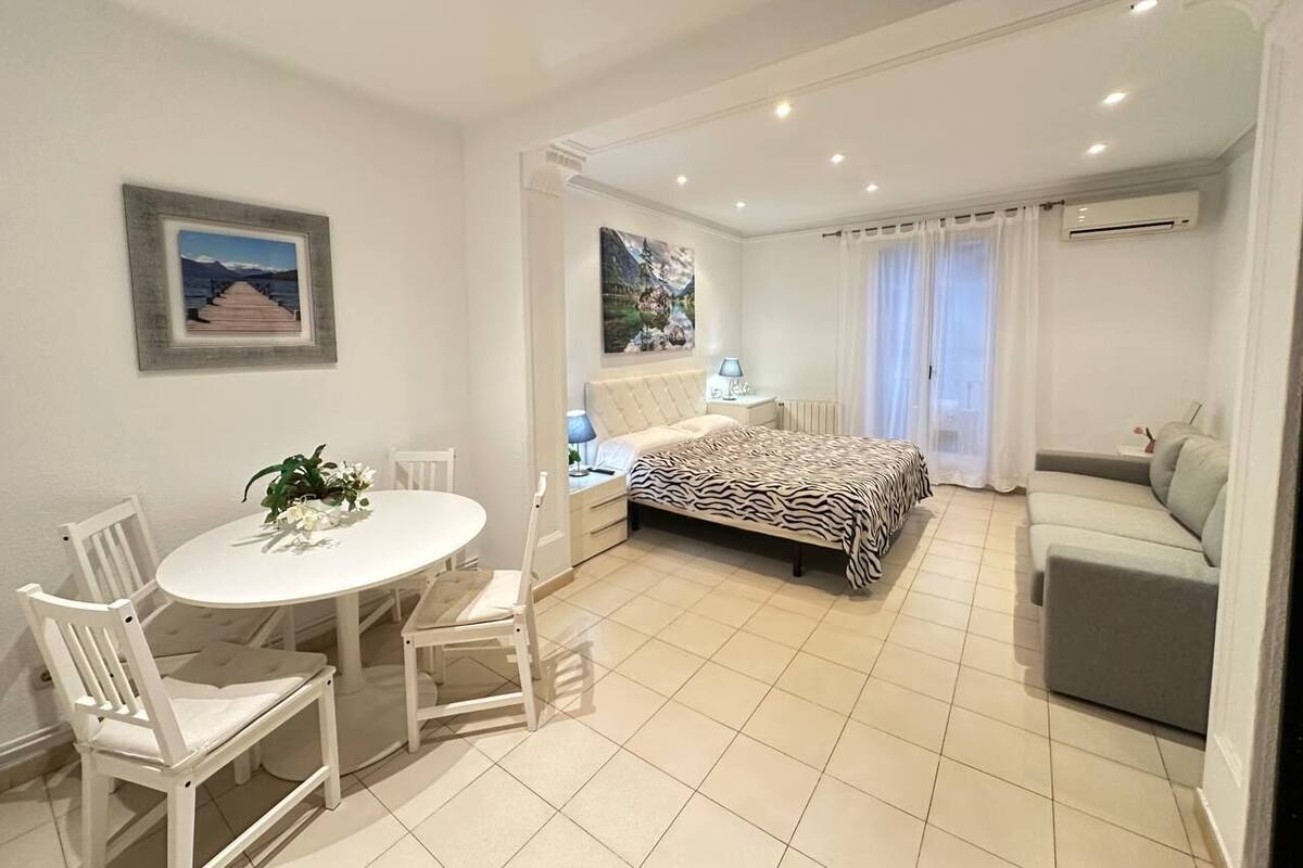 Un dormitorio moderno con una cama, un sofá, una mesa de comedor con sillas y un cuadro en la pared.