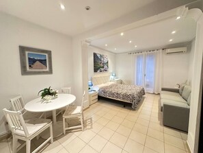 A modern bedroom with a bed, a sofa, a dining table with chairs, and a painting on the wall. - Rooms Consell de cent (Barcelona)