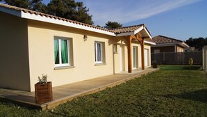 A modern house with a tiled roof, a wooden deck, and a grassy yard. - Family home 1000m from the ocean (Vensac)