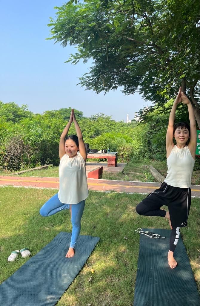 Two individuals practicing yoga outdoors on mats.
