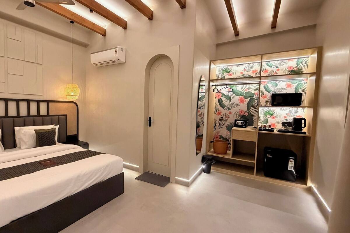 Ein modernes Schlafzimmer mit einem großen Bett, einem Schrank mit tropischem Wandpapier und einer Klimaanlage an der Wand.