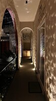 A corridor with stone walls, a glass door, and a staircase with metal railings.