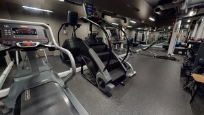 Une salle de sport équipée de tapis de course, de vélos elliptiques et d'appareils de musculation.