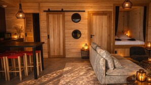 A cozy cabin interior with a wooden interior, a sofa, a dining area with stools, and a bed with a view. - Unusual accommodation with jacuzzi and paddle (Mostuéjouls)