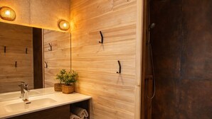 A modern bathroom with a wooden vanity, a large mirror, a sink, and a shower area. - Unusual accommodation with jacuzzi and paddle (Mostuéjouls)