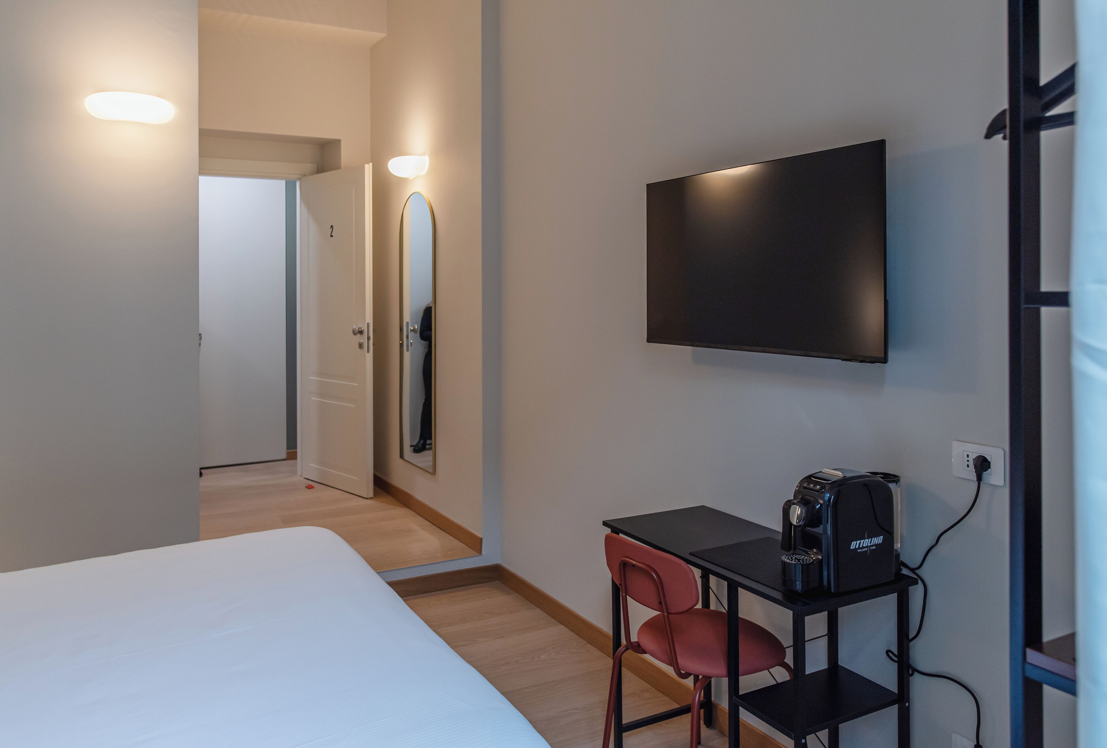 A hotel room with a bed, a desk with a chair, a flat-screen TV, and a coffee maker.