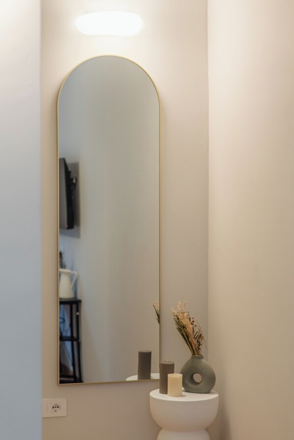 A bathroom with a large mirror, a white pedestal, a vase with dried flowers, and a candle. - San Gregorio Rooms Milano Centrale (Milan)