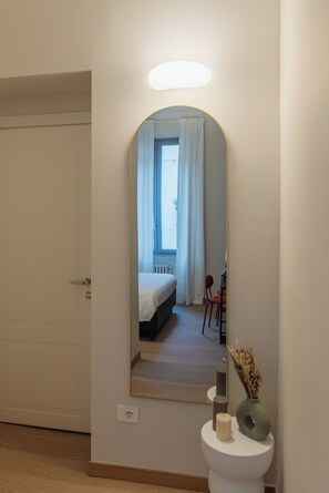 A room with a bed, a chair, a small table, a mirror, and a toilet. - San Gregorio Rooms Milano Centrale (Milan)