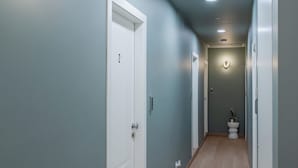 Un pasillo con paredes azul claro, suelo de madera y puertas blancas.