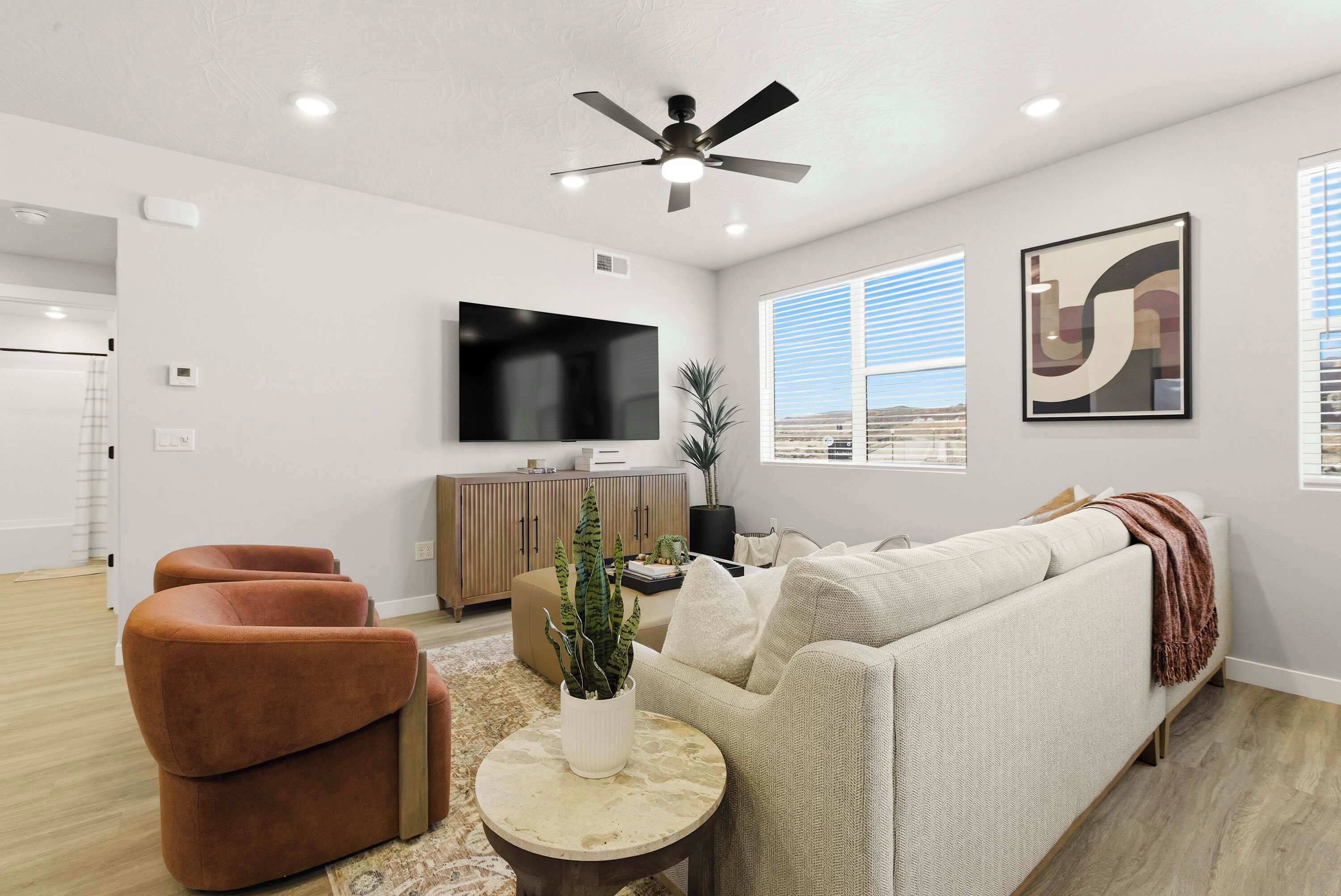 A modern living room with a sofa, armchairs, a coffee table, and a flat-screen TV on the wall.