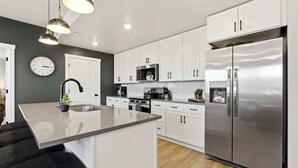 Una cocina moderna con armarios blancos, electrodomésticos de acero inoxidable y una isla central.