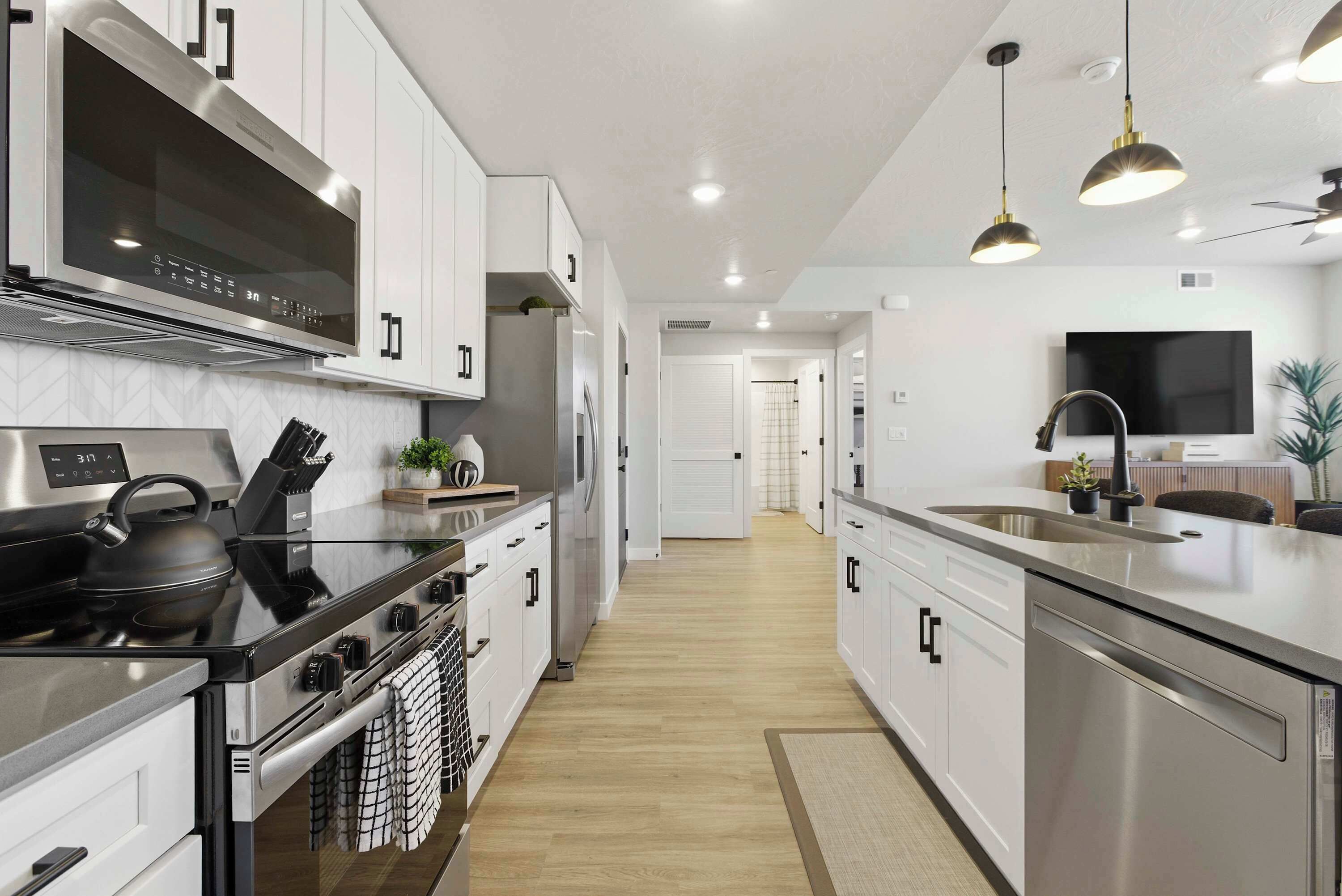 Une cuisine moderne dotée d’appareils électroménagers en acier inoxydable, de meubles blancs et d’un îlot central.