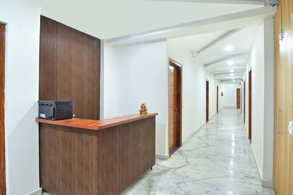 A hotel reception area with a wooden reception desk, a marble floor, and a long corridor with doors on both sides.