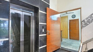 Un moderno ascensor con detalles metálicos y una puerta de madera al lado.