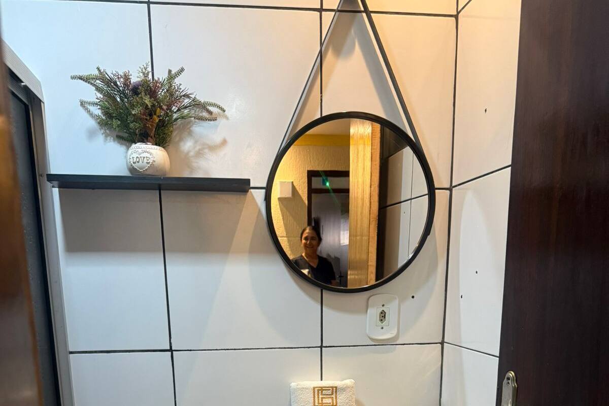 A compact bathroom with a white toilet, a sink with a mirror above it, and a small trash bin.