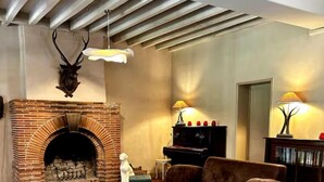 Ein gemütliches Wohnzimmer mit Kamin aus Ziegelsteinen, Ledersofas, einem Couchtisch und einem Fernseher.