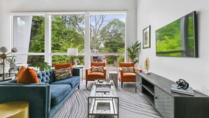 Uma sala de estar moderna com um sofá, poltronas, uma mesa de centro e uma lareira.