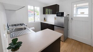 A modern kitchen with white countertops, dark cabinets, a stainless steel refrigerator, and a microwave. - Affordable house, walk to South Bank, CBD & transport (South Brisbane)