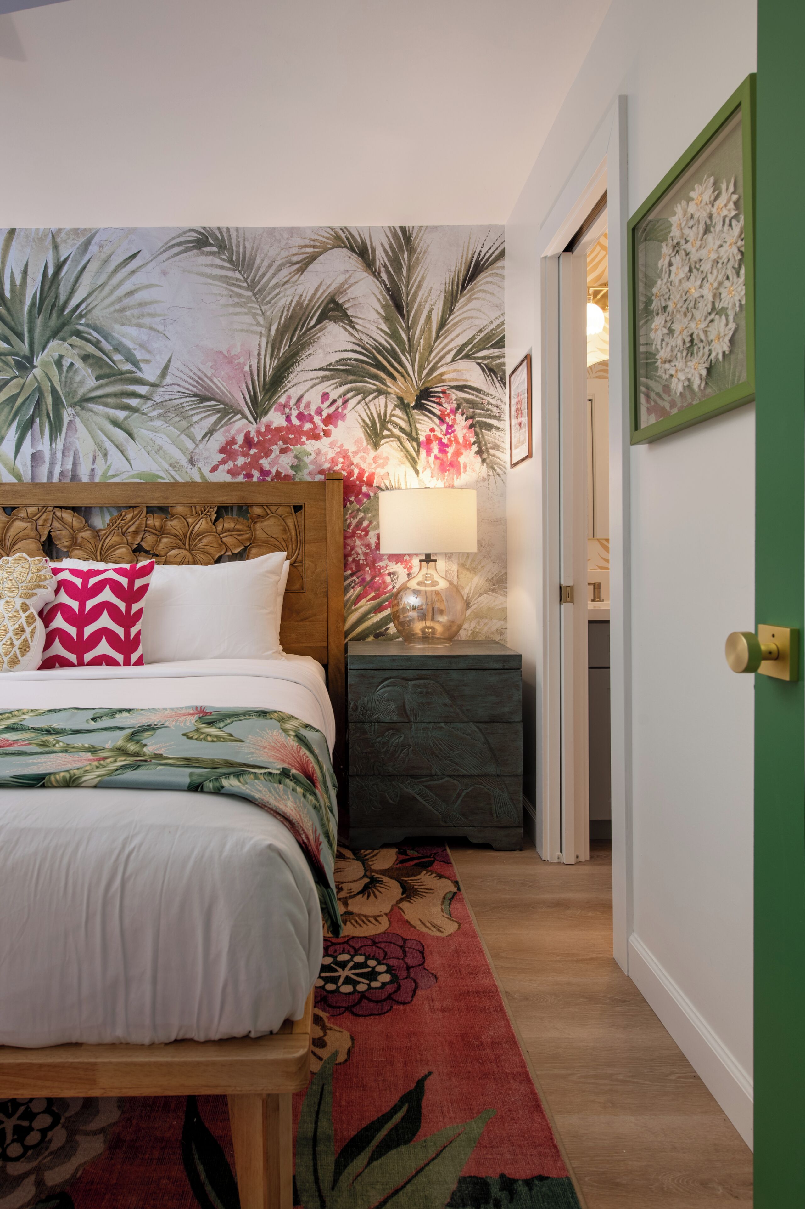 A bedroom with a bed, a nightstand, a lamp, and a door.
