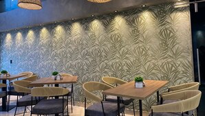 Un intérieur moderne avec un papier peint à motifs, des tables en bois et des chaises en osier.