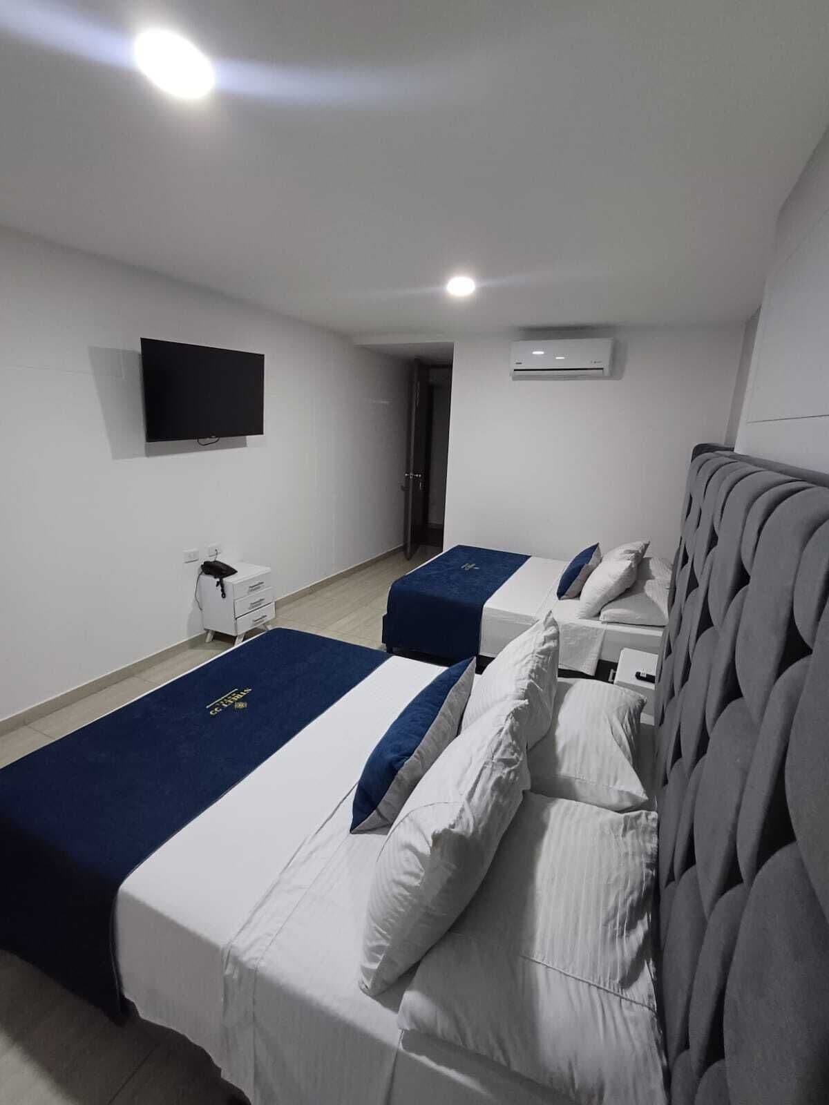 Quarto de hotel com duas camas, televisão, ar condicionado e telefone.