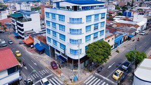 Un hôtel à plusieurs étages, doté d’une façade bleue et blanche, situé à un carrefour de la ville, où la circulation est visible, ainsi que les bâtiments environnants.
