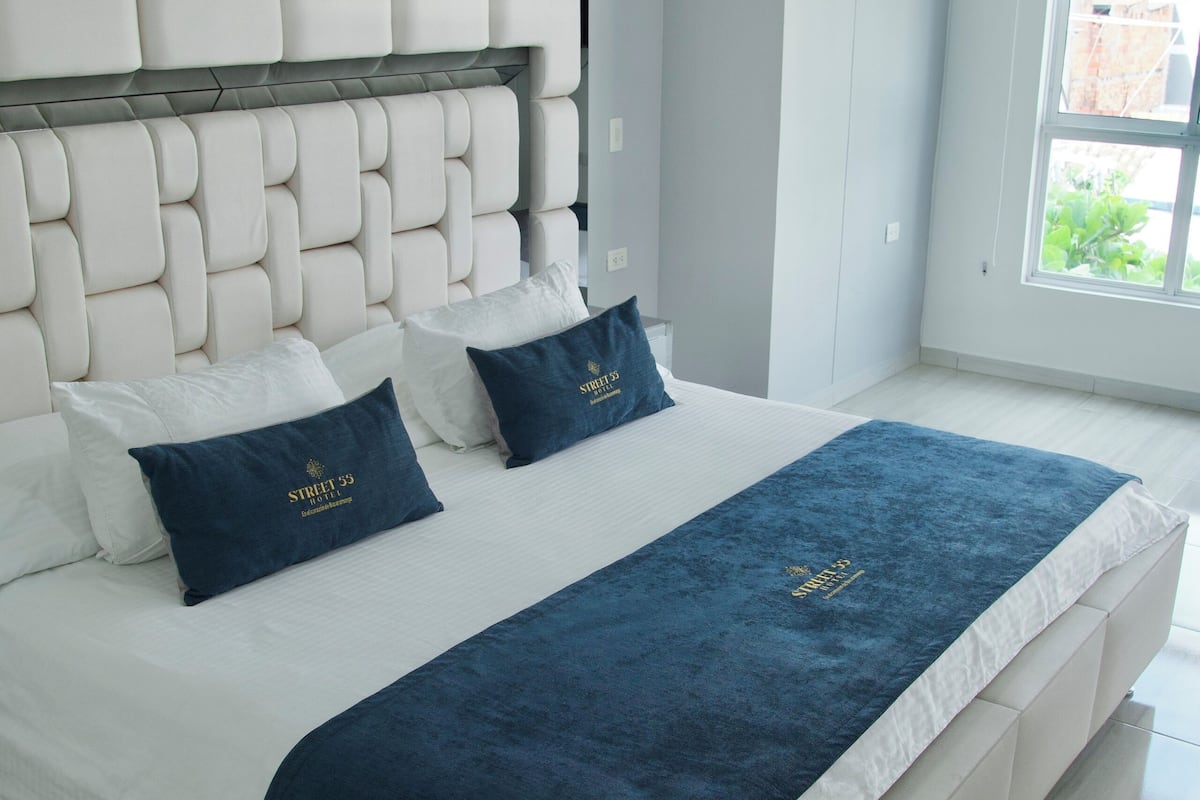 Ein modernes Schlafzimmer mit einem großen Bett, weißer Bettwäsche und einer dunkelblauen Tagesdecke.