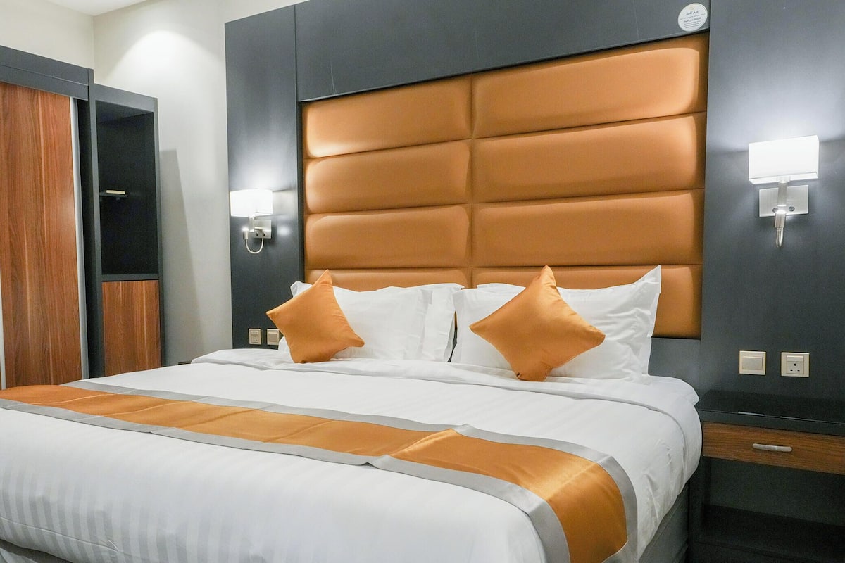 Una habitación de hotel con una cama grande, un armario de madera y un cabecero moderno.
