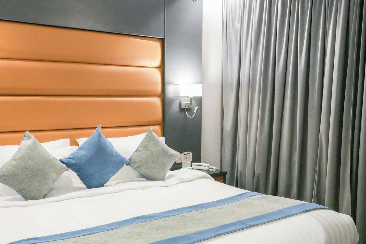 Una habitación de hotel con una cama grande, un cabecero y una mesita de noche.