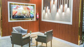 Ein modernes Interieur mit an der Wand montiertem Fernseher, einem Feuerlöscher und einer Sitzecke mit Tisch und Stühlen.