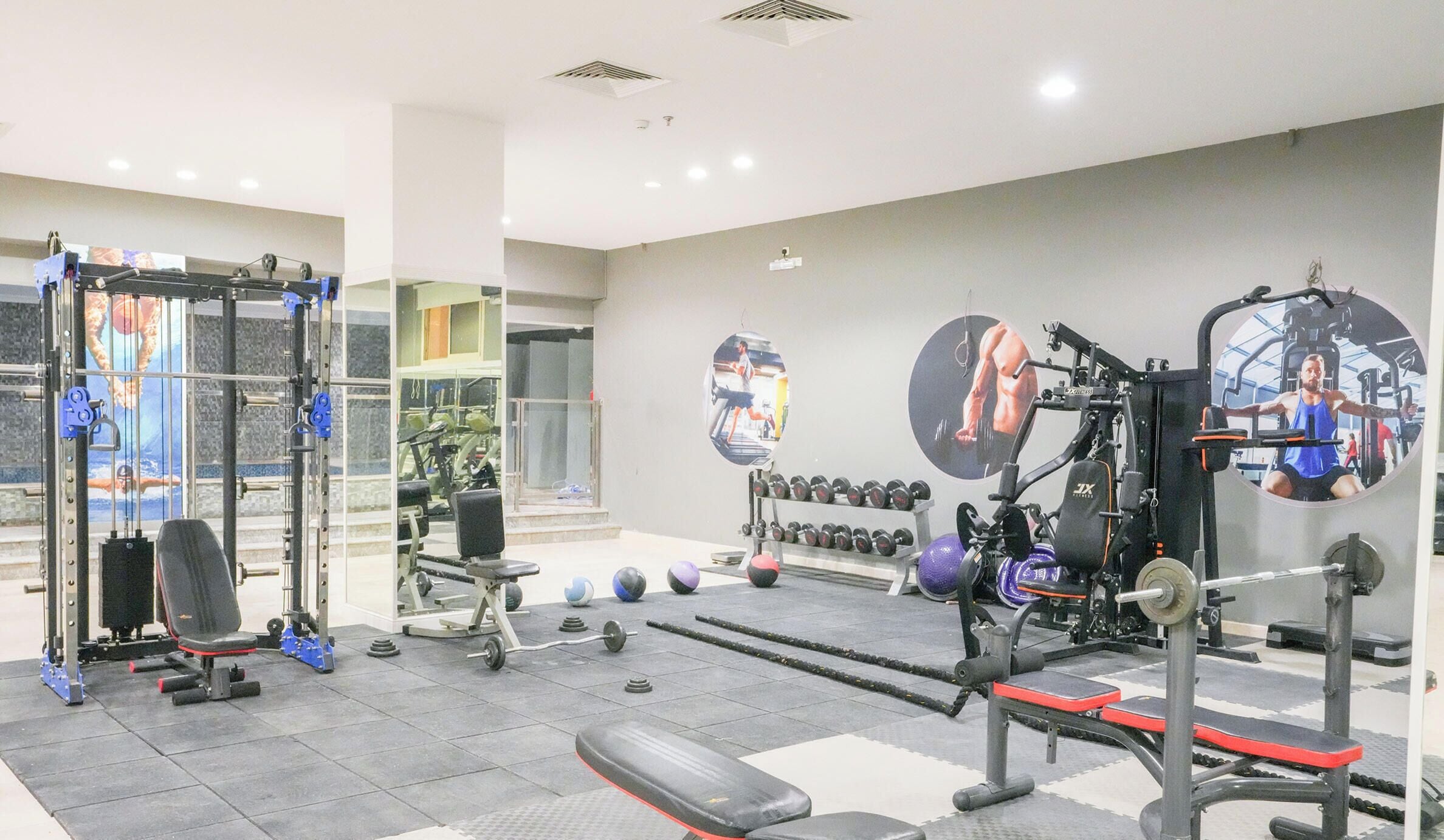Un gimnasio con equipo de levantamiento de pesas, cintas de correr y balones de ejercicio.