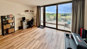A spacious living area with a large window, a desk, and a workout bench. - Charming Flat Near London Attractions (Sheerwater)