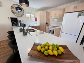 A modern kitchen with a central island, a built-in oven, and a refrigerator.